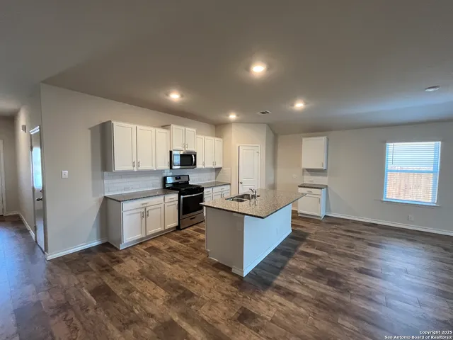 a large kitchen with a sink and dishwasher a stove top oven with wooden floor