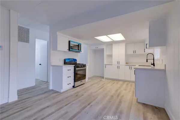 a kitchen with stainless steel appliances granite countertop a sink cabinets and wooden floor