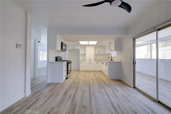 a view of kitchen and empty room with wooden floor