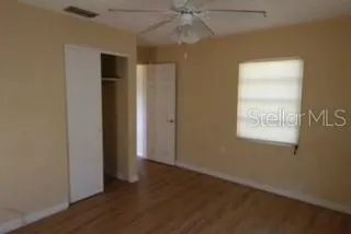 an empty room with wooden floor closet and windows