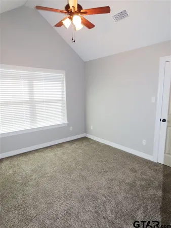 an empty room with a ceiling fan and carpet