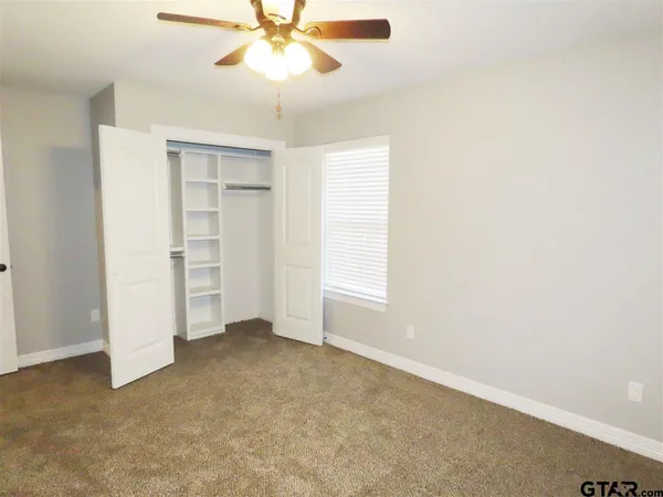 an empty room with closet and a chandelier fan