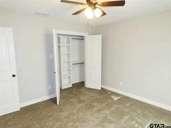 an empty room with a window and a fan