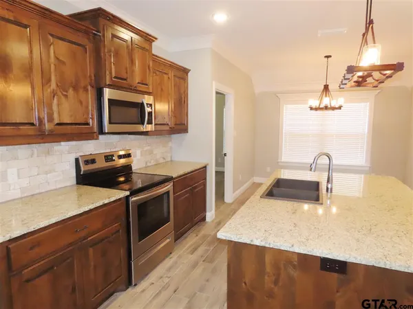 a kitchen with stainless steel appliances kitchen island granite countertop a sink a stove and microwave