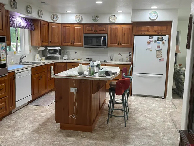 a kitchen with stainless steel appliances granite countertop a refrigerator a sink a stove a microwave and island