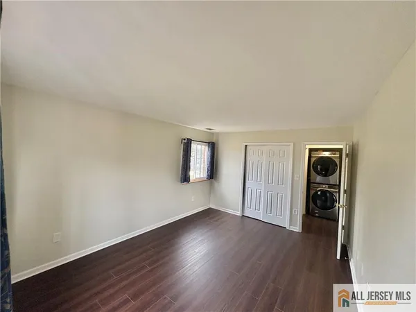 an empty room with wooden floor closet and windows
