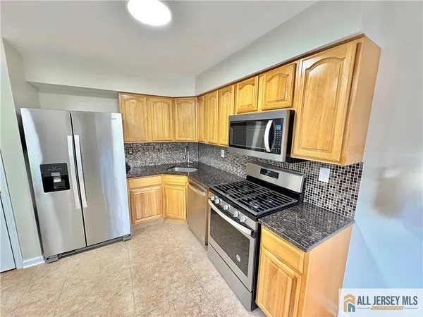 a kitchen with stainless steel appliances granite countertop a stove a sink and a refrigerator