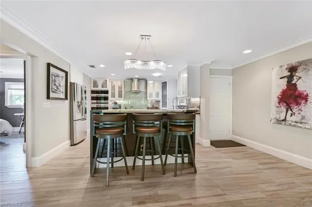a kitchen with stainless steel appliances kitchen island granite countertop a dining table chairs and white cabinets