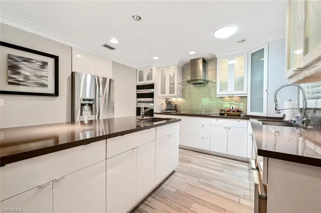 a large kitchen with stainless steel appliances a large counter top a stove and a refrigerator