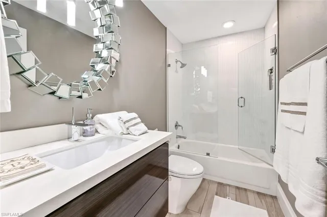 a bathroom with a granite countertop sink a toilet a mirror and shower