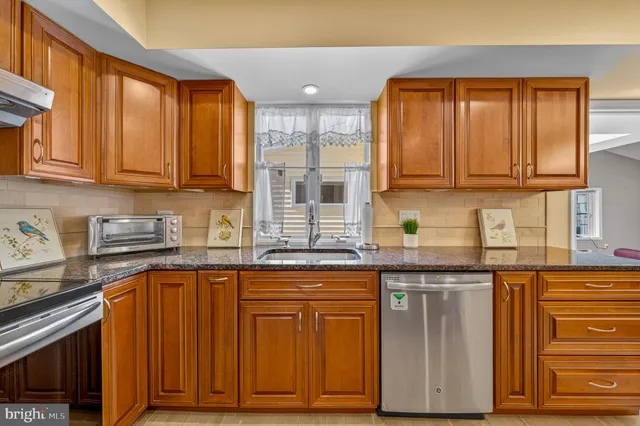 a kitchen with stainless steel appliances granite countertop a refrigerator a sink and a stove