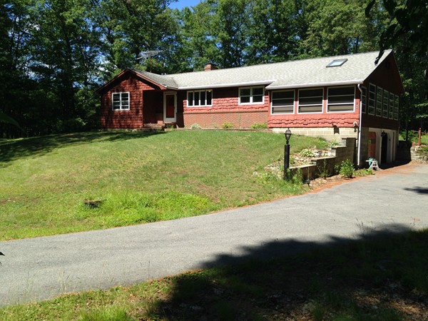 a front view of house with yard and trees in the background