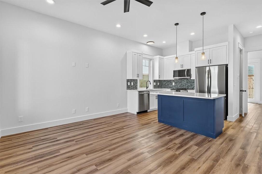 232 Nautilus Port Aransas, TX 78373 - Photo 5 of 28 a kitchen with stainless steel appliances kitchen island granite countertop a refrigerator a stove and a wooden floors