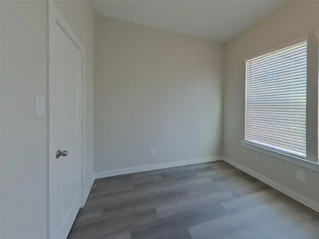 a view of an empty room with wooden floor and closet