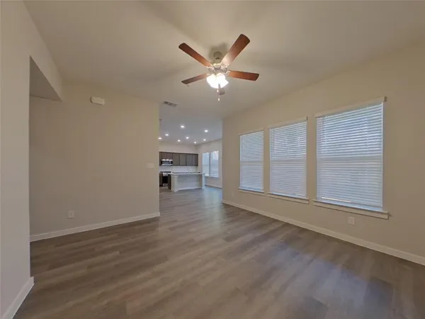 a view of an empty room with a window and wooden floor