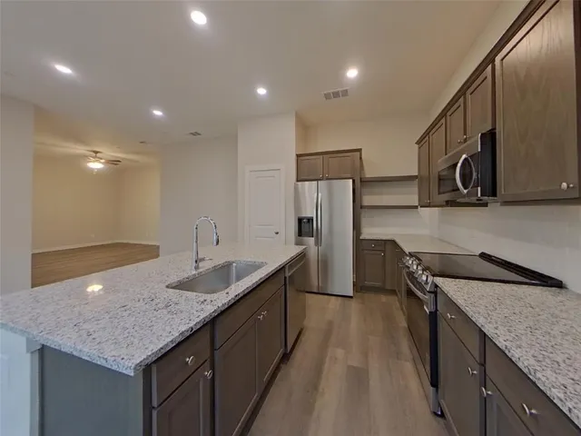 a kitchen with kitchen island granite countertop wooden cabinets and refrigerator