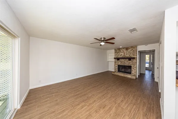 an empty room with wooden floor fireplace and windows