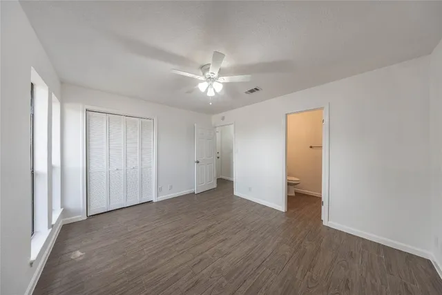 an empty room with wooden floor and a ceiling fan