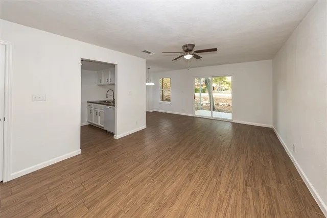 an empty room with wooden floor chandelier and windows