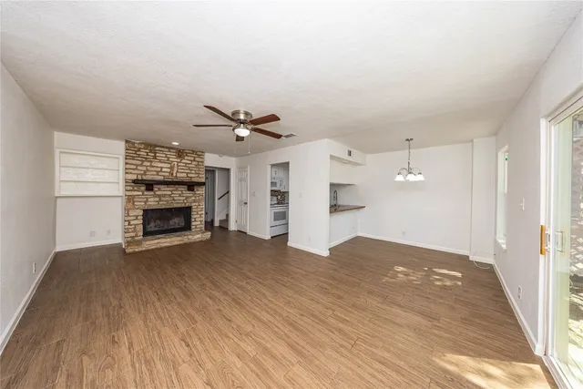an empty room with wooden floor fireplace and windows