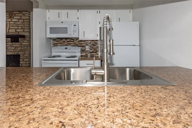 a kitchen with stainless steel appliances granite countertop a sink a stove and a refrigerator