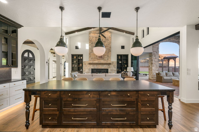 4871 South Homestead Way Washington, UT 84780 - Photo 150 of 151 Kitchen featuring arched walkways, dark wood finish cabinets, a kitchen bar, glass fronted cabinets, and open floor plan