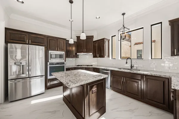 a kitchen with granite countertop kitchen island stainless steel appliances a sink stove and refrigerator
