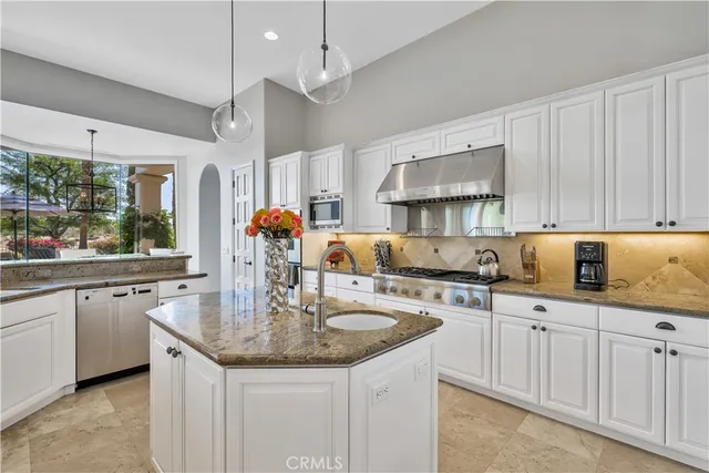 a kitchen with stainless steel appliances granite countertop a sink a stove and a wooden floors