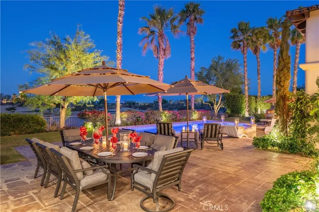 a view of a patio with a dining table and chairs under an umbrella with a barbeque