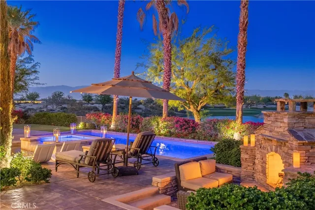 a view of swimming pool with table and chairs potted plants and palm tree
