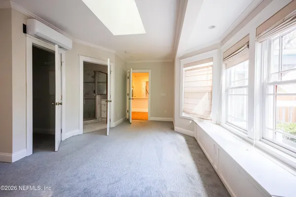 a view of an empty room with a window and a kitchen