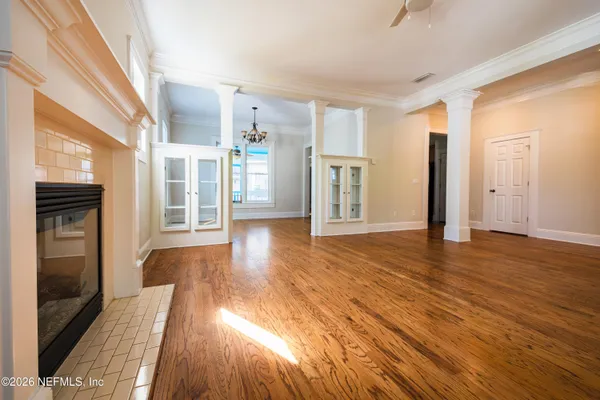 a view of an empty room with window and wooden floor