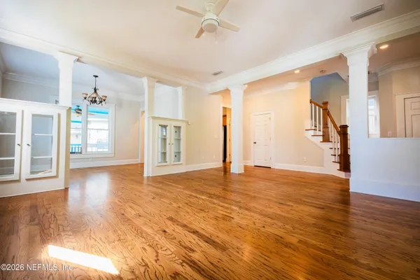 an empty room with wooden floor fireplace and windows