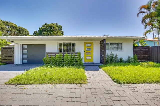 a front view of a house with a yard and potted plants