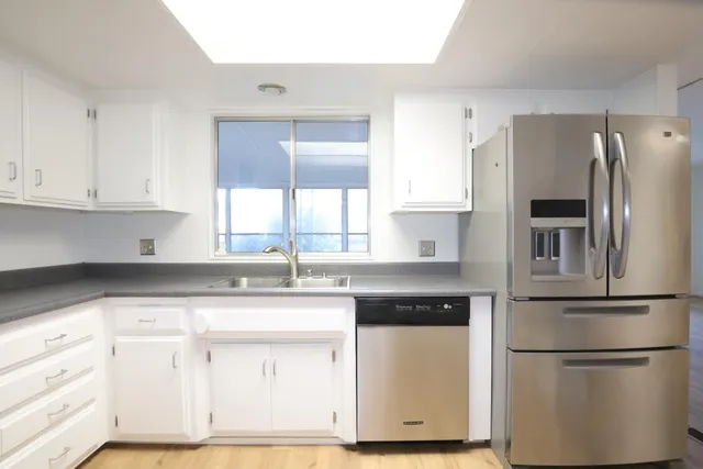 a kitchen with stainless steel appliances a refrigerator and a wooden floor