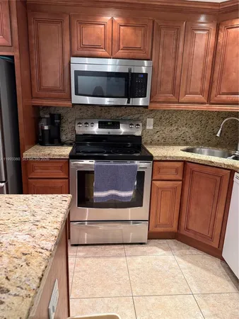a kitchen with granite countertop a stove top oven microwave and cabinets