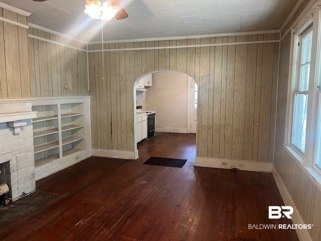 321 Grant Street Chickasaw, AL 36611 - Photo 6 of 13 Unfurnished living room featuring arched walkways, a ceiling fan, dark wood finished floors, wood walls, and a fireplace