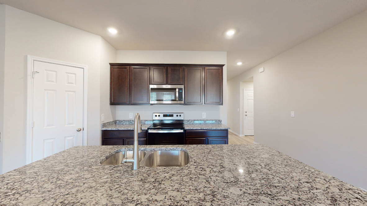 575 Hector Loop Georgetown, TX 78626 - Photo 4 of 28 Kitchen island featuring an undermount double basin stainless steel sink and granite countertop