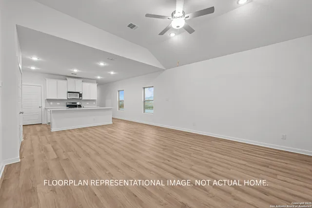 an empty room with chandelier fan and windows