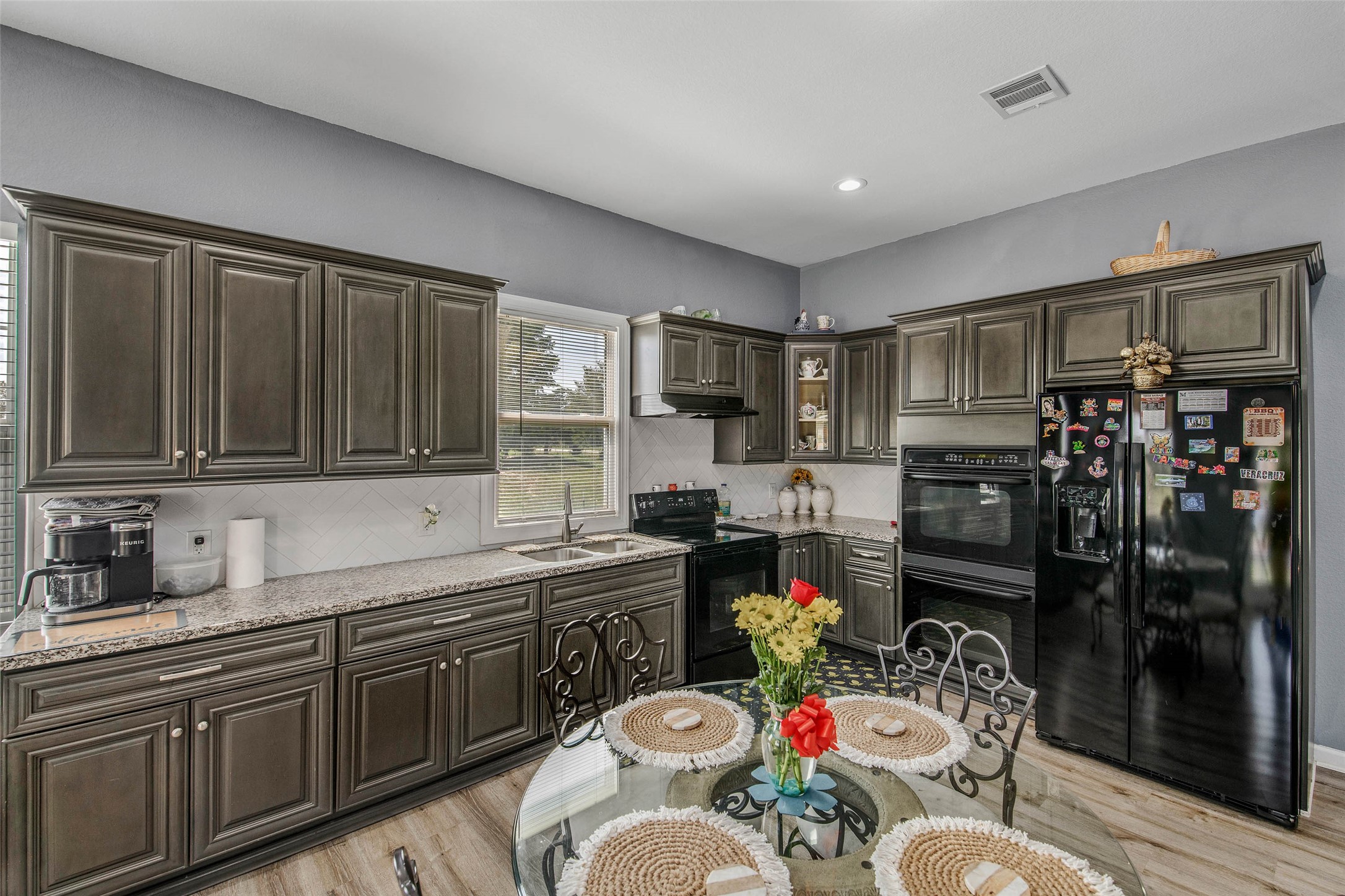 3876 Hummingbird Lane Bedias, TX 77831 - Photo 4 of 29 a kitchen with stainless steel appliances kitchen island granite countertop a sink dishwasher cabinets a dining table and chairs with wooden floor