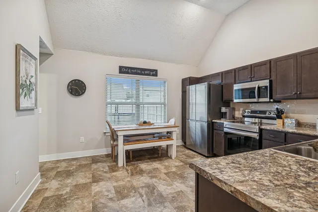a kitchen with granite countertop a refrigerator and a stove top oven