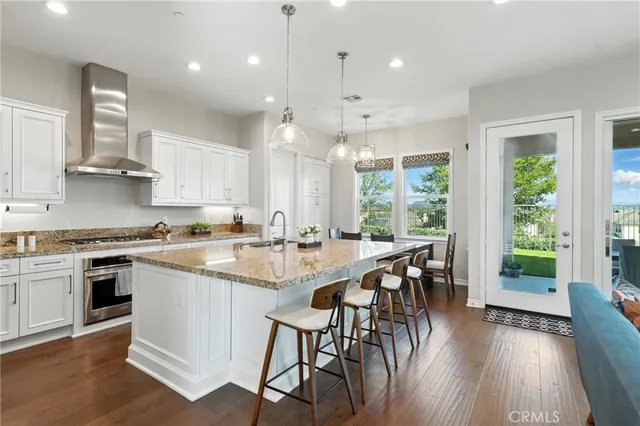 a large kitchen with kitchen island a large island in the center a sink a window cabinets and stainless steel appliances