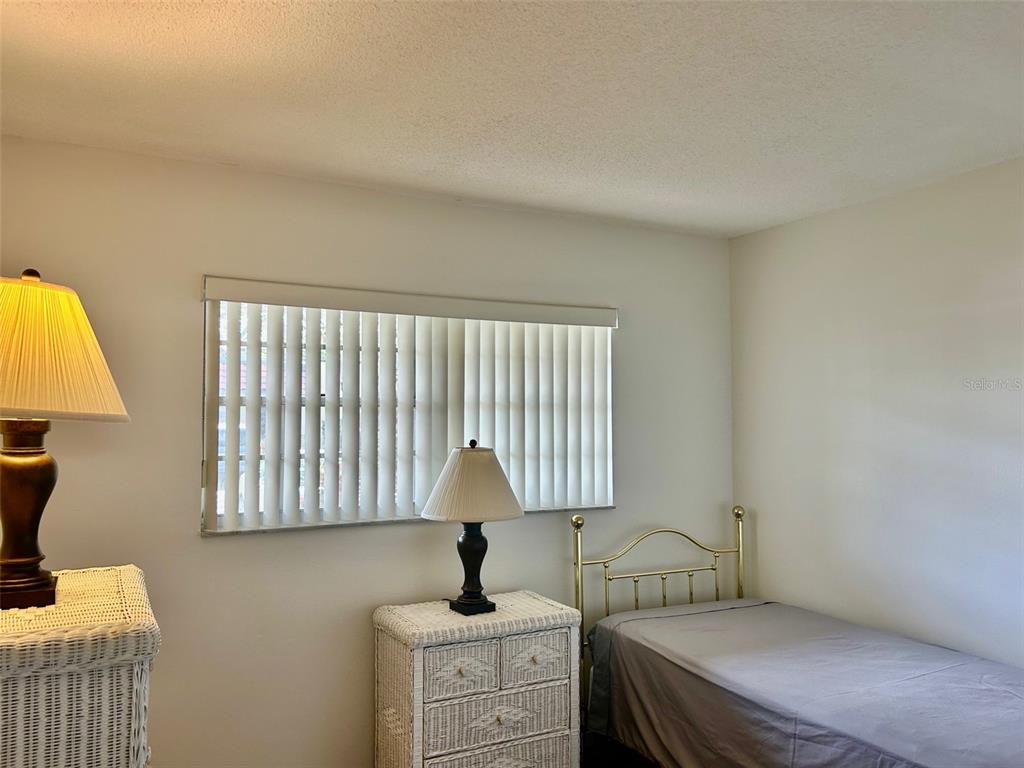 1701 Pinehurst Road, Unit 18C Dunedin, FL 34698 - Photo 11 of 17 a bedroom with a bed a lamp and a window