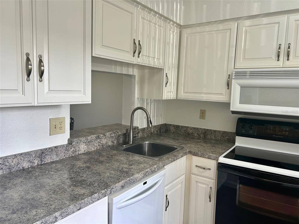 1701 Pinehurst Road, Unit 18C Dunedin, FL 34698 - Photo 2 of 17 a kitchen with granite countertop a sink and cabinets
