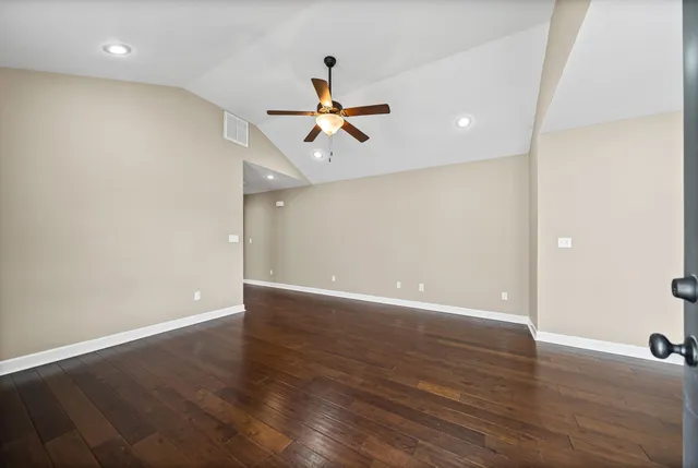 an empty room with wooden floor ceiling fan and window
