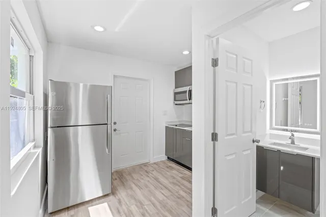 a bathroom with a refrigerator sink and mirror