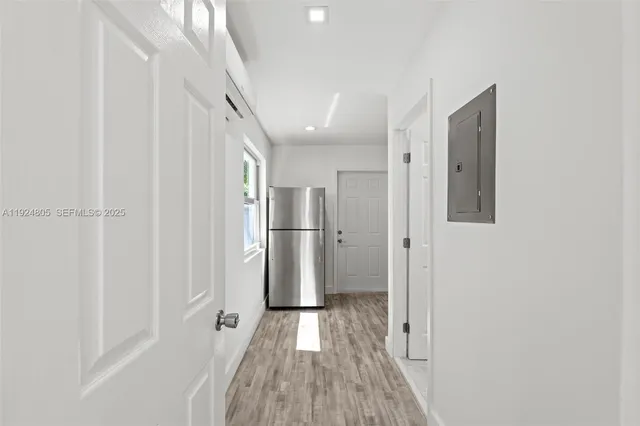 a view of a hallway with wooden floor and a refrigerator