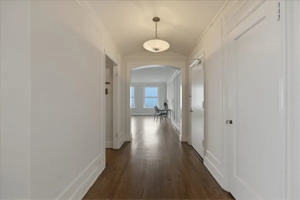 a view of a hallway with wooden floor and a bathroom