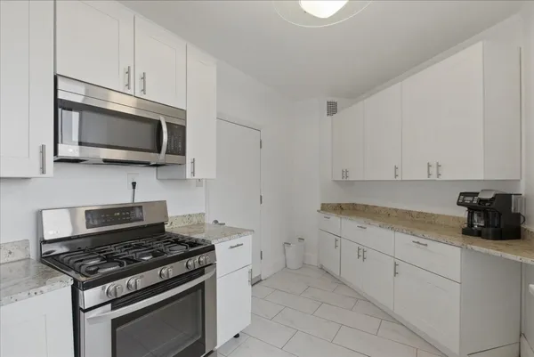a kitchen with granite countertop a stove top oven microwave and cabinets
