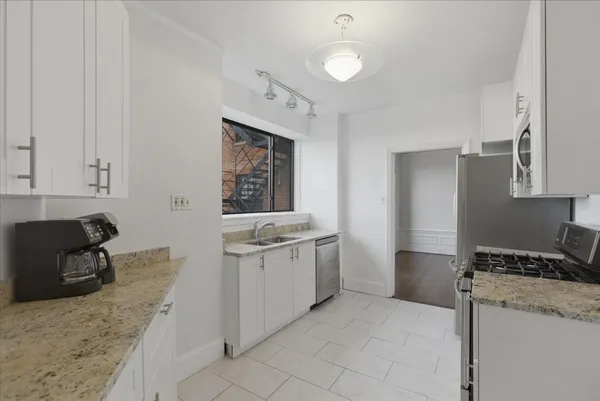 a kitchen with granite countertop a sink stove and refrigerator